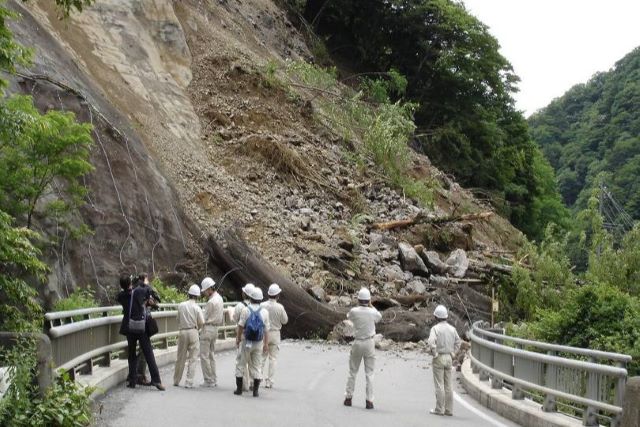 がけ地形が崩落して道路を覆い、通行不能になっている写真。