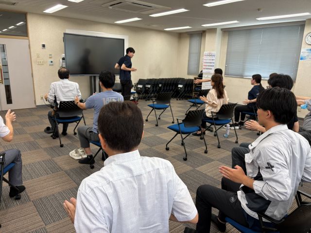 肩甲骨を寄せるストレッチを行う社員一同
